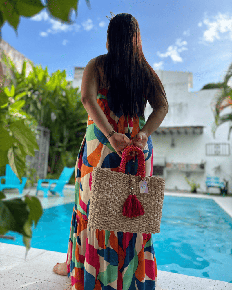 Mujer de espaldas con canasto elaborado en palma de iraca con borlas beige y aza beige