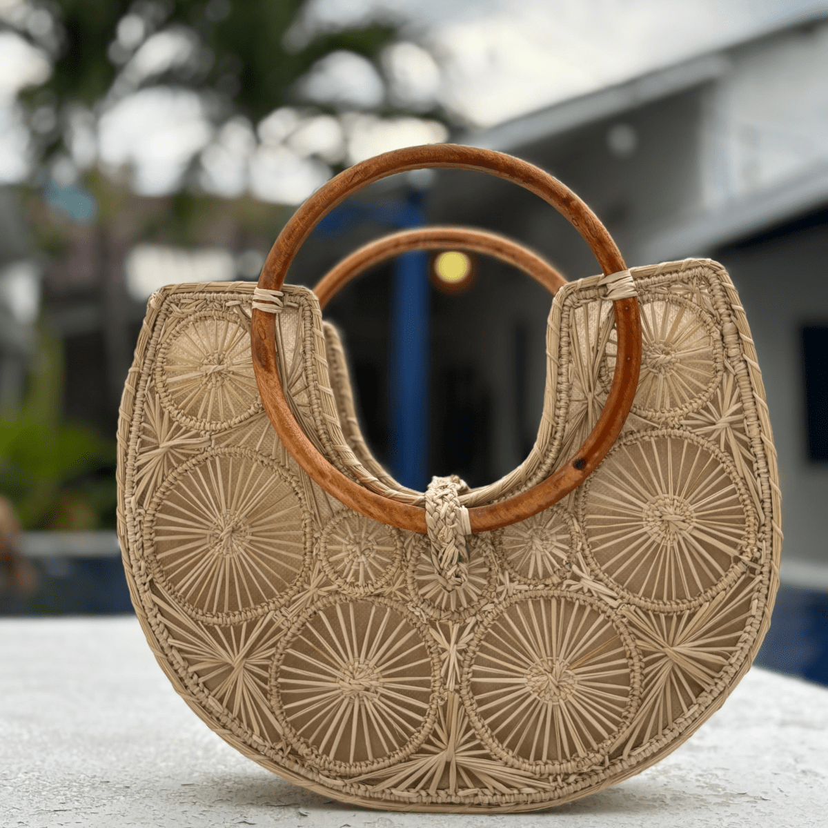 Bolso elaborado en palma de iraca en forma de media luna con aza de madera