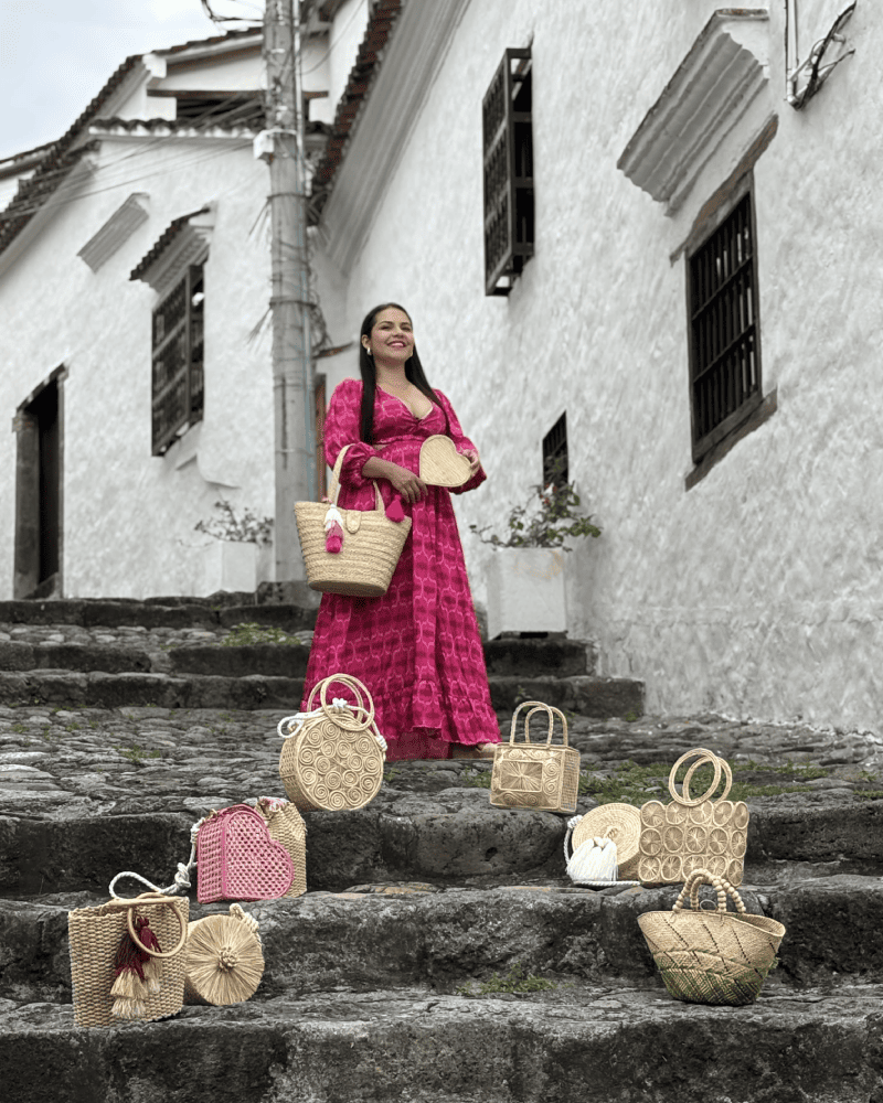 Mujer bajando unas escaleras rodeada de productos en palma de iraca