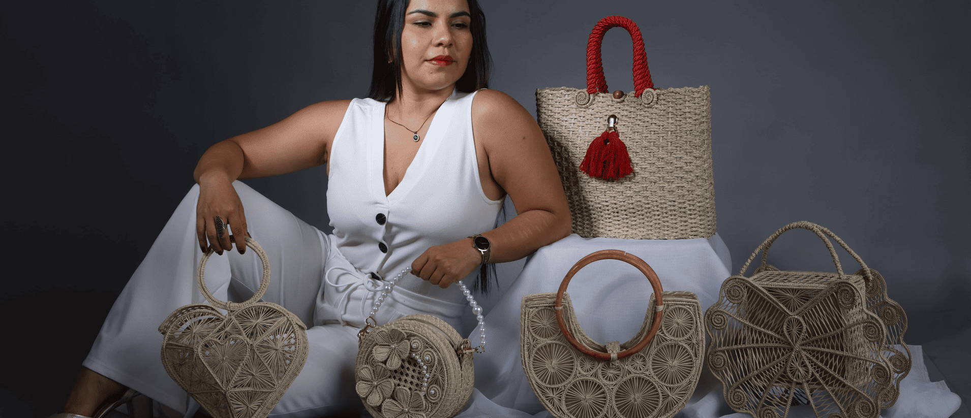 Mujer sentada con varios bolsos en palma de iraca