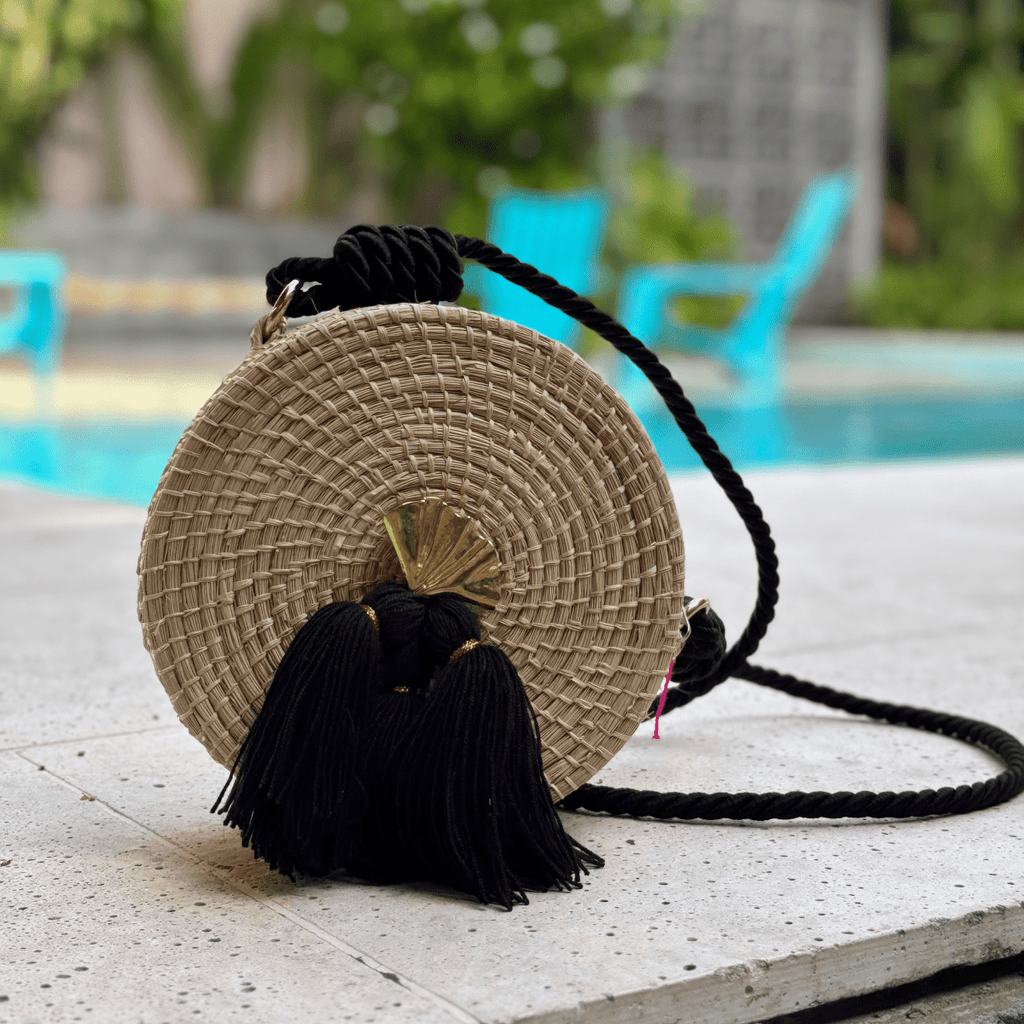 Bolso yoyo redondo en palma de iraca liso con herraje, borlas color negro y lazo color negro