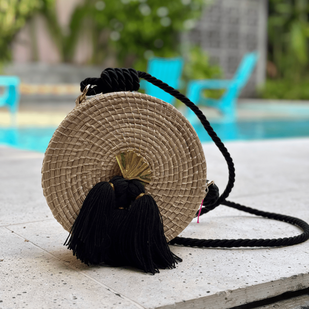 Bolso yoyo redondo en palma de iraca liso con herraje, borlas color negro y lazo color negro